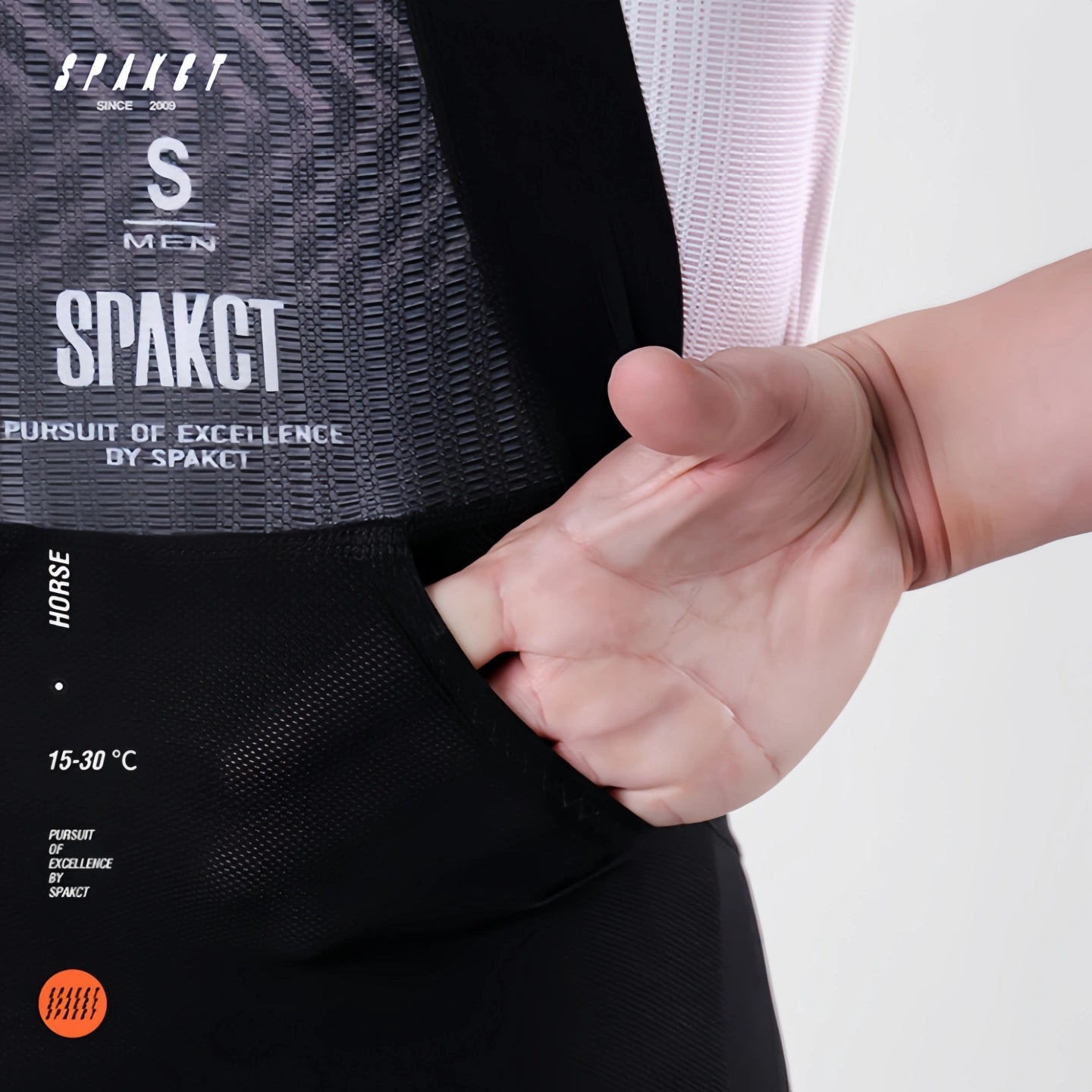 Close-up of integrated rear mesh storage pocket on the waist panel of Spakct Horse men's long road bike bibs.
